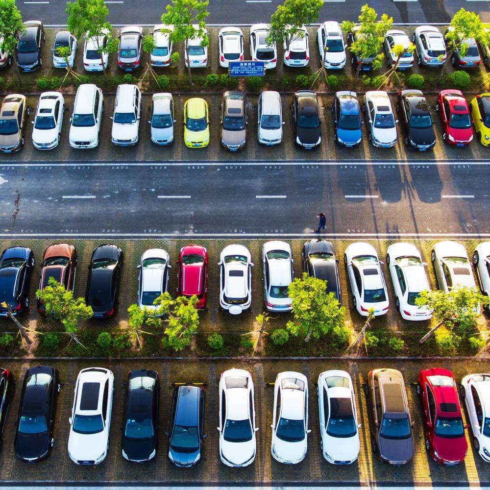 Many cars, equipped with GPS trackers, are parked in a parking lot.