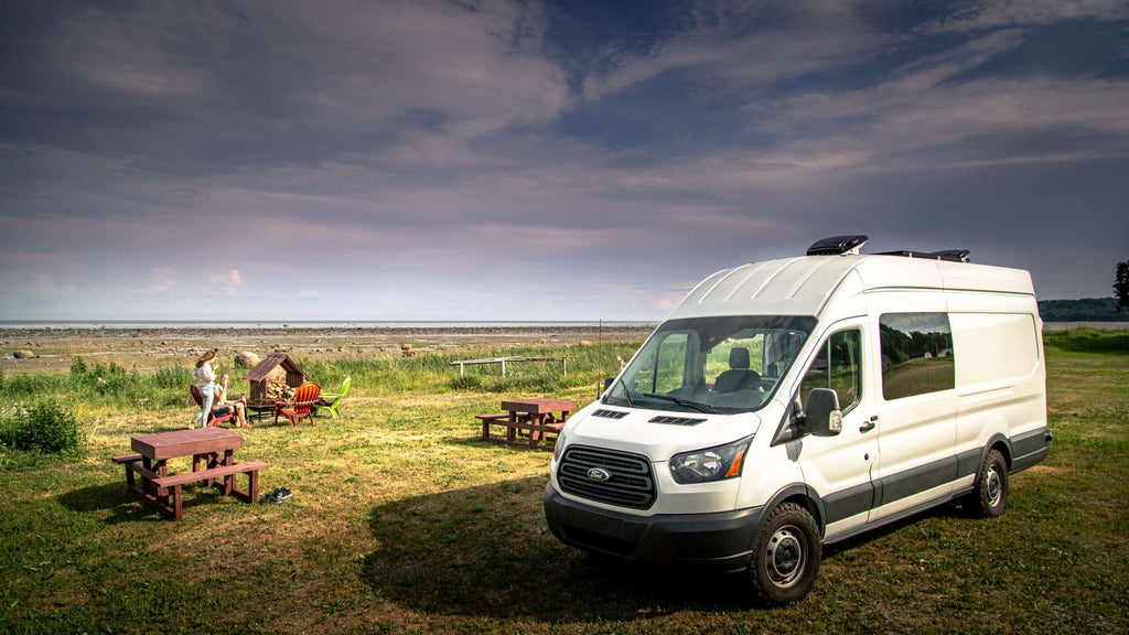 A Ford Transit van parked in a grassy area.